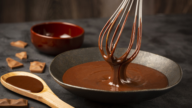 whisk dipping into bowl of warm chocolate ganache