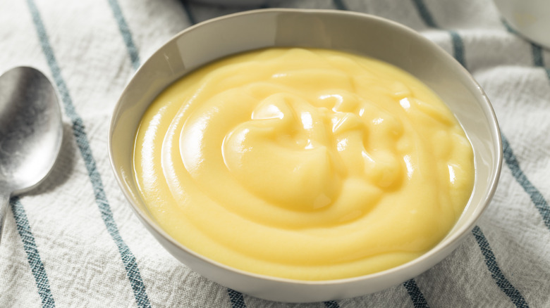 bowl of thick vanilla custard on towel next to metal spoon