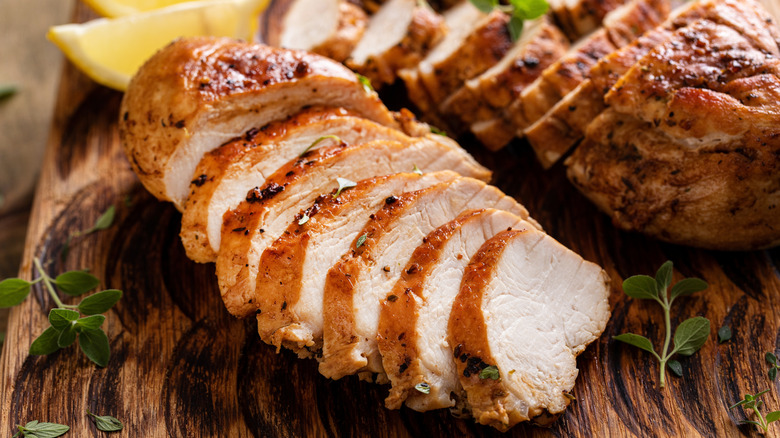 Sliced cooked chicken breast on wooden board
