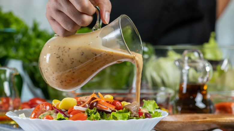 Salad dressing being poured over salad