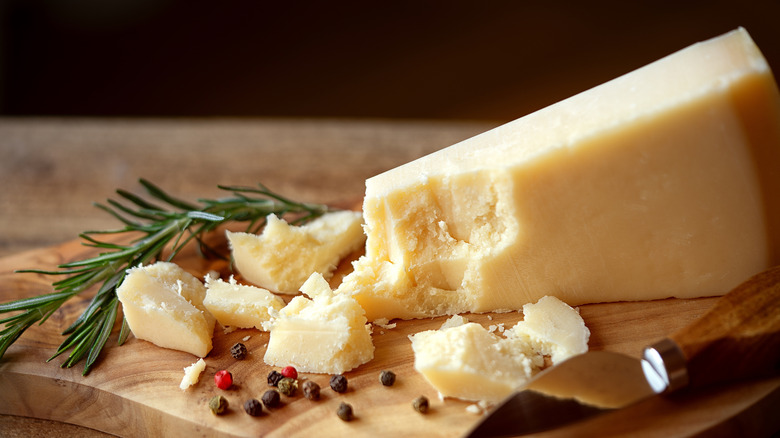 Wedge of Parmigiano Reggiano with whole peppercorns and fresh rosemary