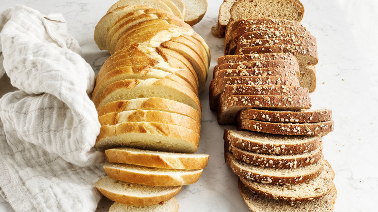 Two loaves of sliced bread on counter with kitchen towel