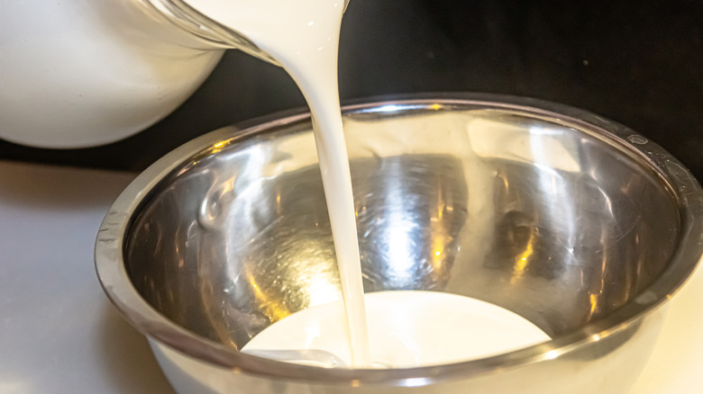 Pouring heavy cream into metal mixing bowl