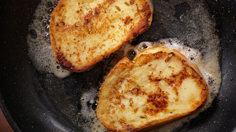 Slices of french toast cooking in a frying pan