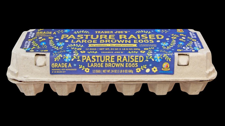 A carton of pasture raised large brown eggs on a black background