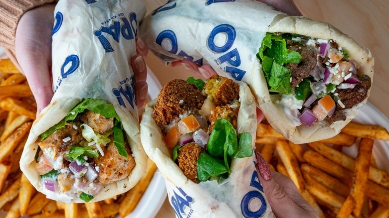 Hands holding wraps from Opa! Of Greece