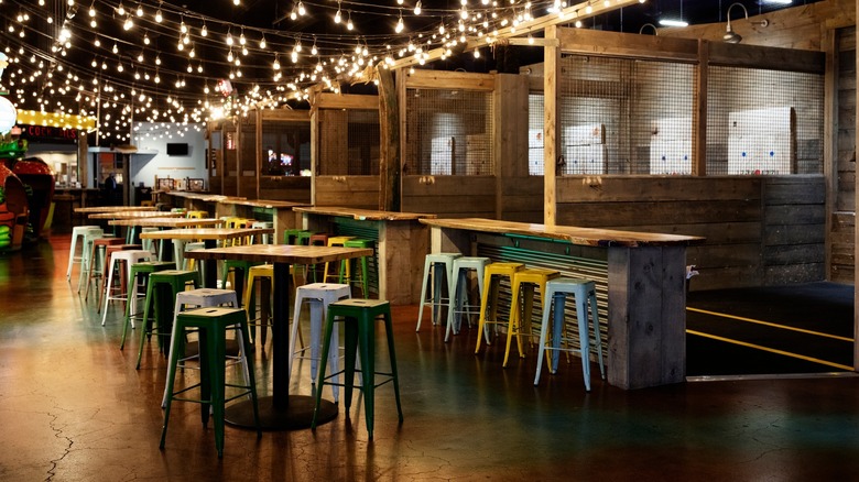 Interior of The Fair on 4 showing tables, axe-throwing stations, and some arcade games