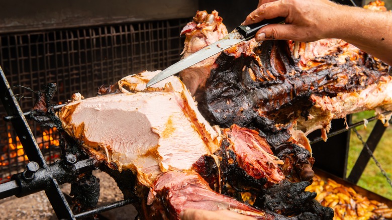 barbecue station with hands cutting meat