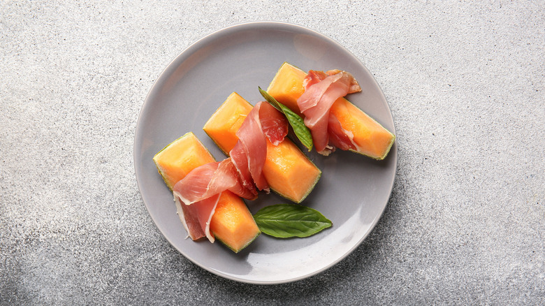 melon, prosciutto, and basil on a plate