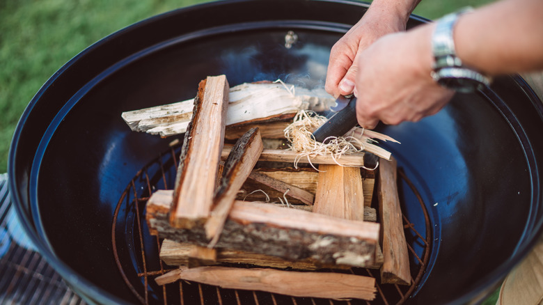 Person lighting a wood grill