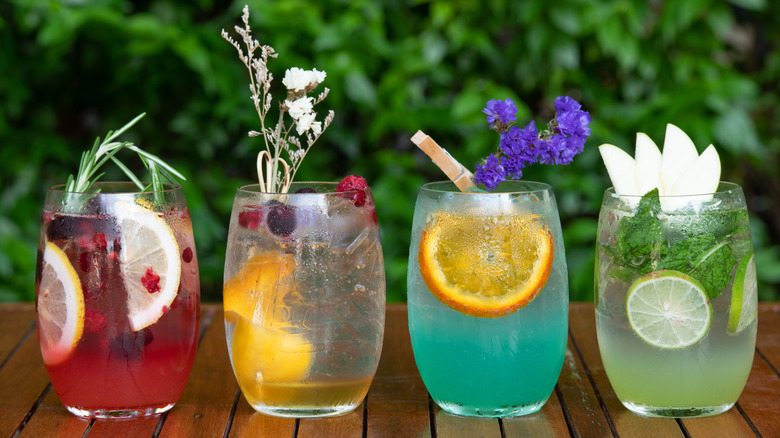 Line up of fruity cocktails with herbal garnish