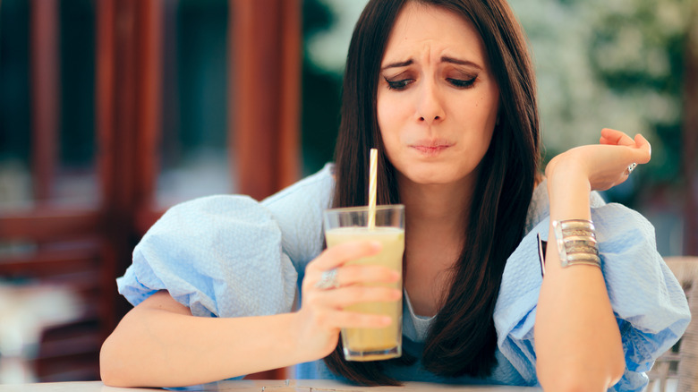 Woman tasting drink with an unpleasant expression on her face