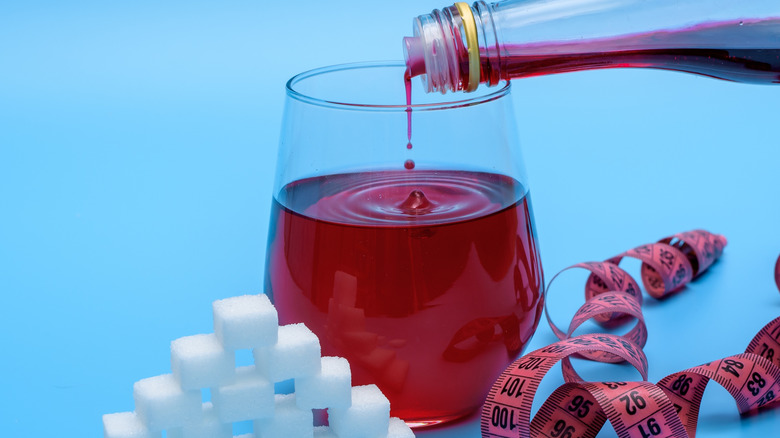 Pouring grenadine into a glass next to pile of sugar cubes