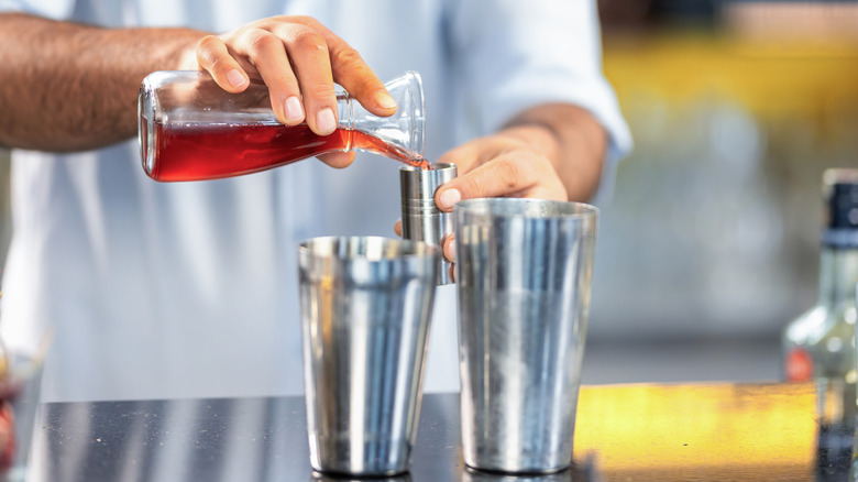 Bartender measuring ingredients for cocktail