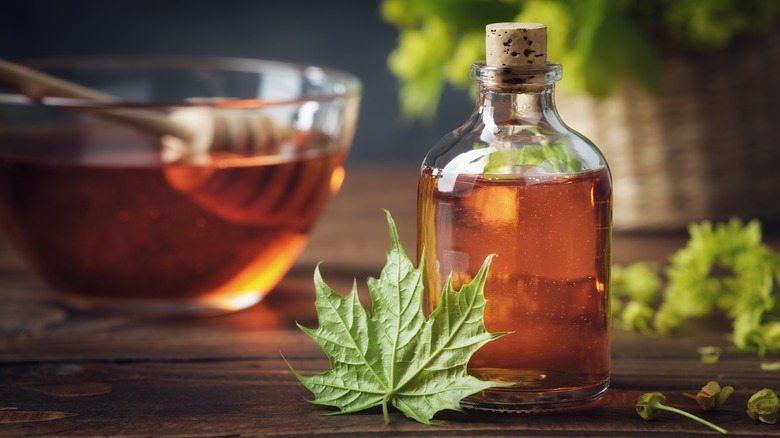 A bottle of maple syrup on a table with a maple leaf