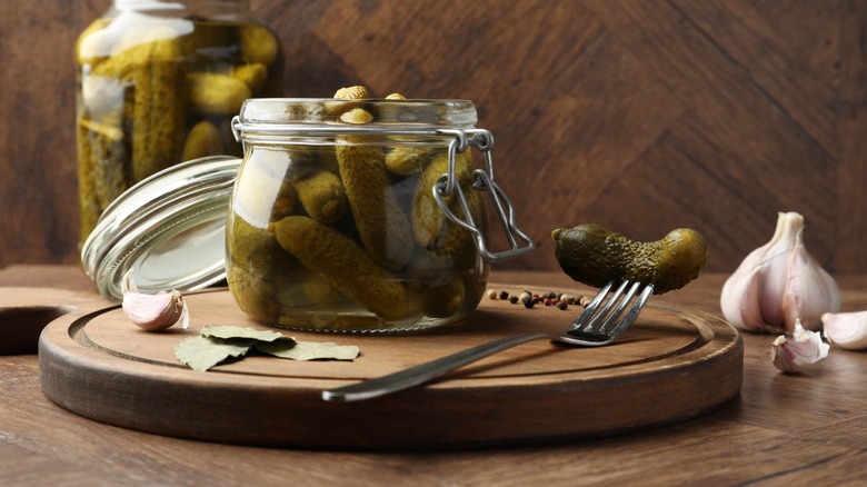A jar of pickled cucumbers on a wooden board