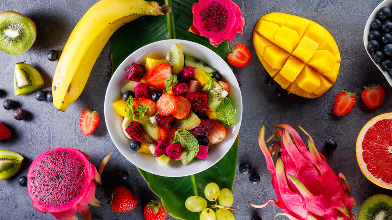 A bolw of tropical fruit surrounded by fruit