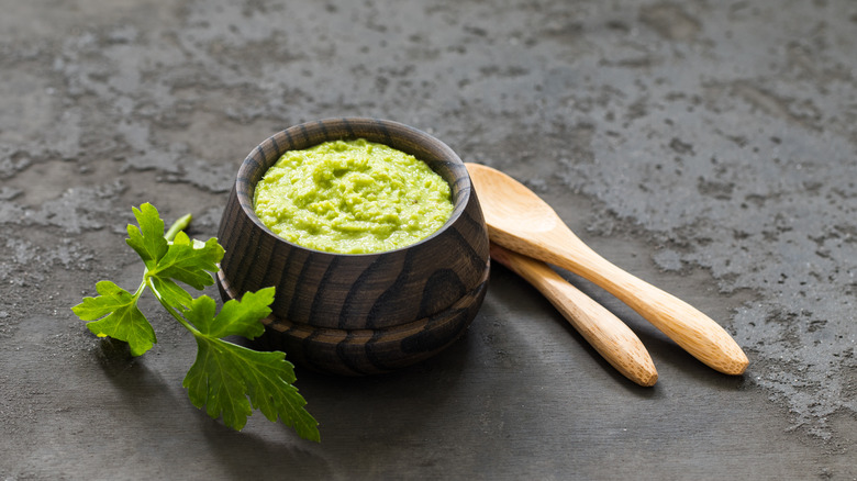 A bowl of wasabi on a table with wooden spoons