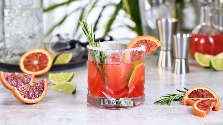 A blood orange margarita cocktail garnished with rosemary and an orange slice