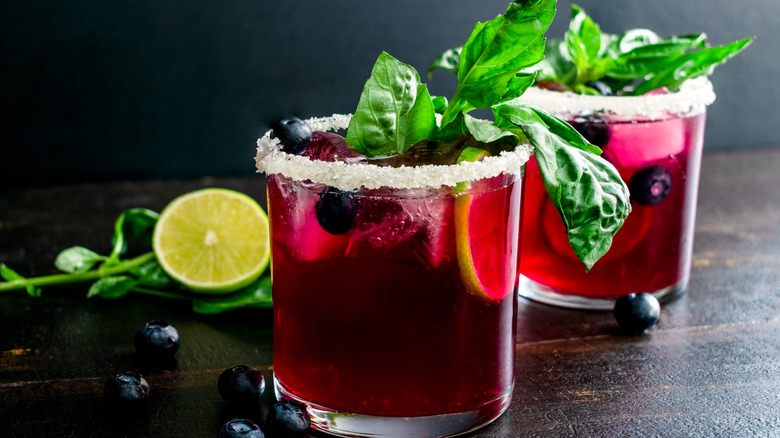 Two blueberry margaritas garnished with lime and basil