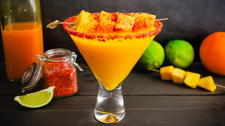 A spicy mango margarita garnished with mango chunks and Tajín