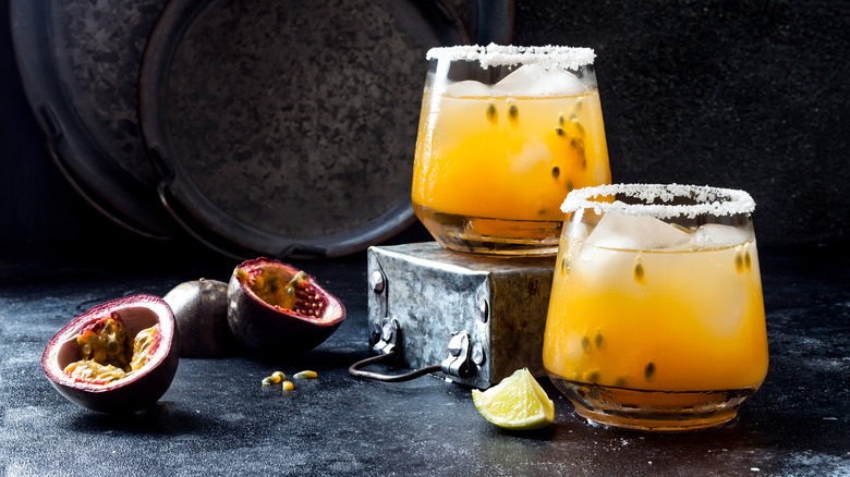 Two passionfruit margarita cocktails in lowball glasses with salted rims