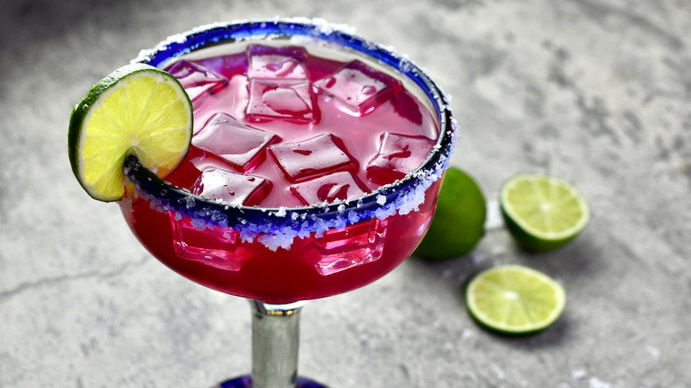 A prickly pear margarita cocktail with a salt rim and a lime slice
