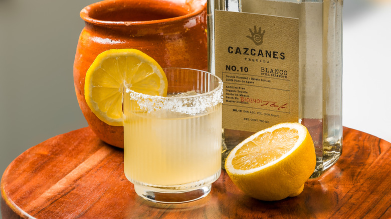 An El Alevado margarita cocktail next to a bottle of Cazcanes Blanco and half a lemon