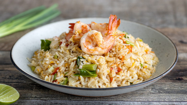 A bowl of shrimp fried rice on a wooden table