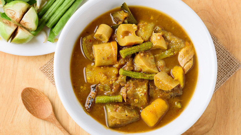 A white bowl with fish curry stew on a wooden table