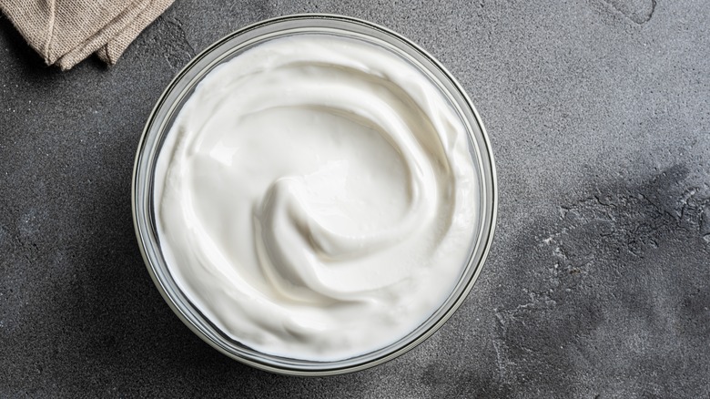 A glass bowl of whipped cream cheese dip on a dark gray counter