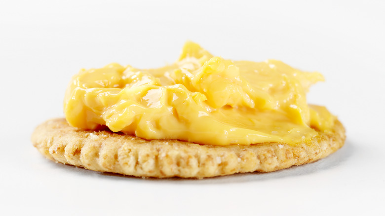 Cheese spread on a cracker on a white background