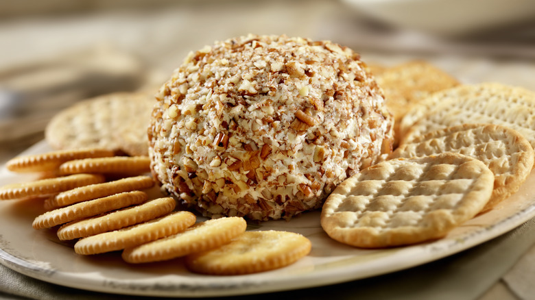 Cheese ball with chopped almonds served with crackers on a plate