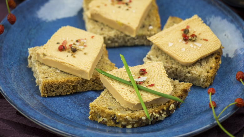 Foie gras served on mini toasts on a blue plate