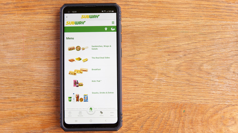 Phone lying on a wooden table open to the Subway food app