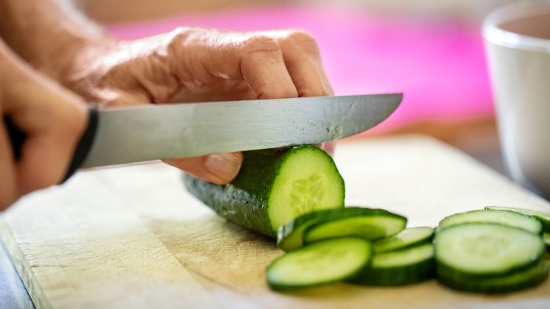 Woman slicing fresh cucumbers