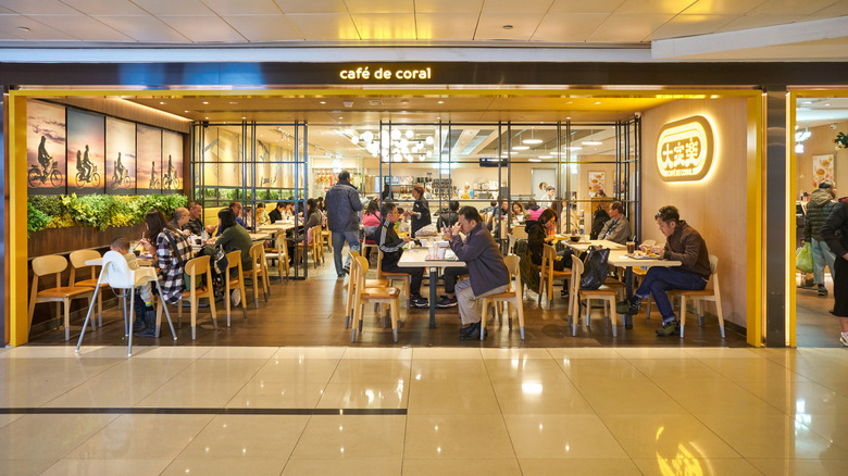 Cafe de Coral storefront in a mall in Hong Kong, showing several customers seated at tables