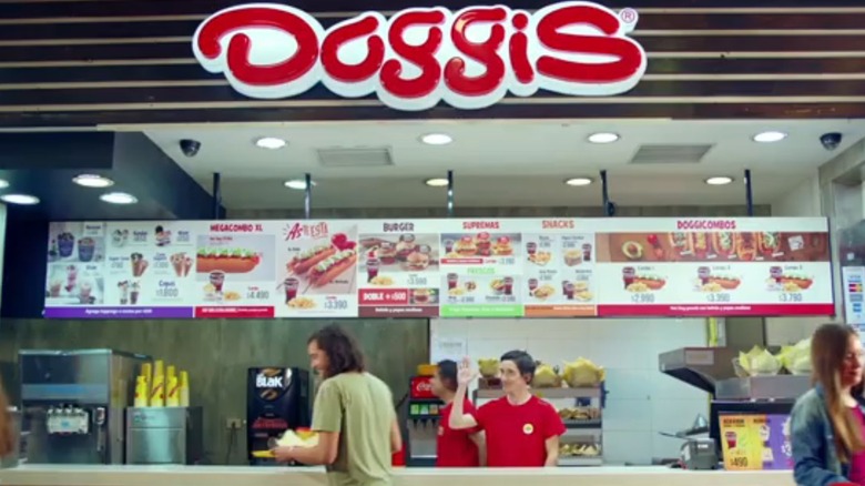 Doggis storefront like you might see in a mall food court, with a waving, smiling cashier and customers getting food