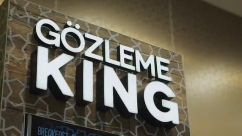 Gozleme King sign with white capital letters on a wood background with a star pattern
