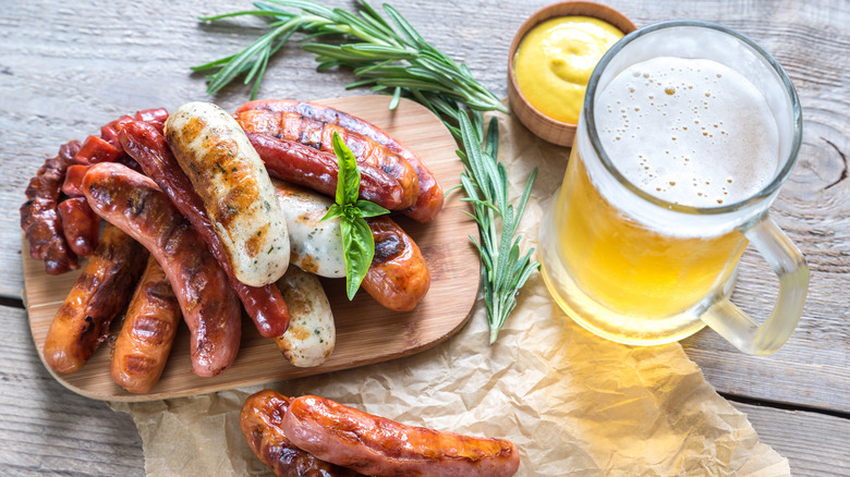 Grilled sausages on a wooden board with a mug of beer