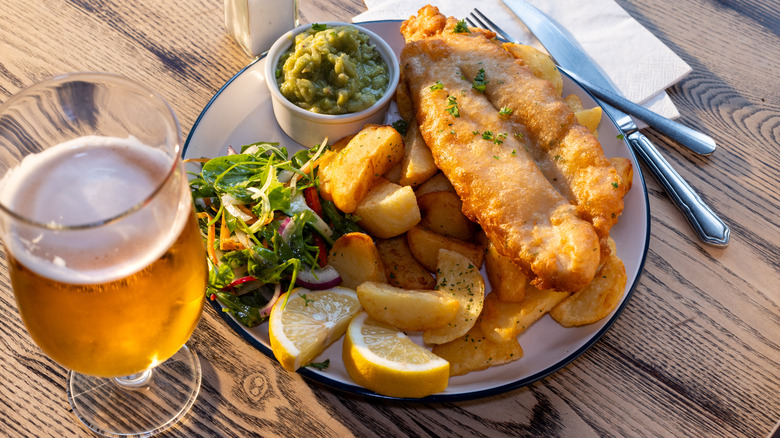 A plate of fish and chips next to a glass of beer