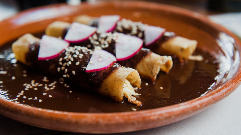 A plate of enchiladas with mole negro