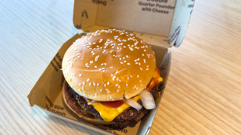 A McDonald's Quarter Pounder with Cheese in a takeout container