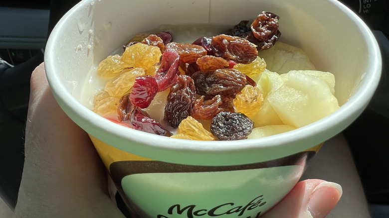 Person holding a cup of oatmeal with fruit from McDonald's