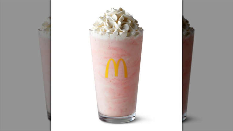 A glass of strawberry milkshake with whipped cream from McDonald's