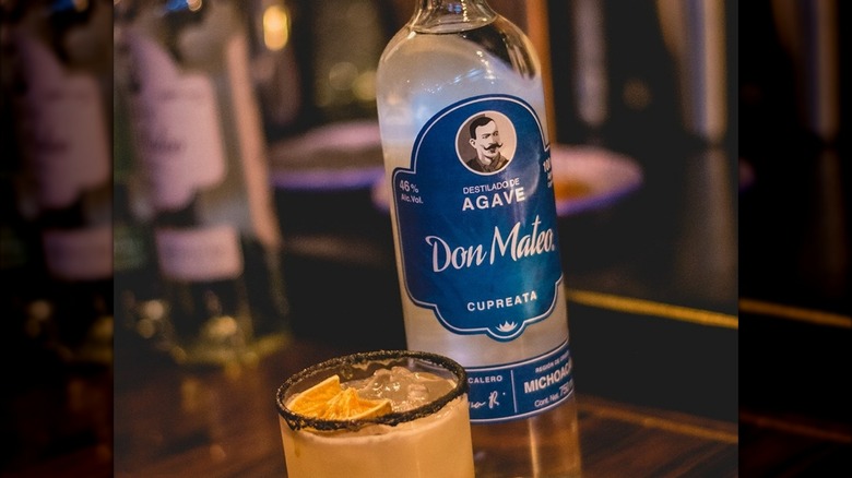 A bottle of Don Mateo Cupreata mezcal next to a cocktail