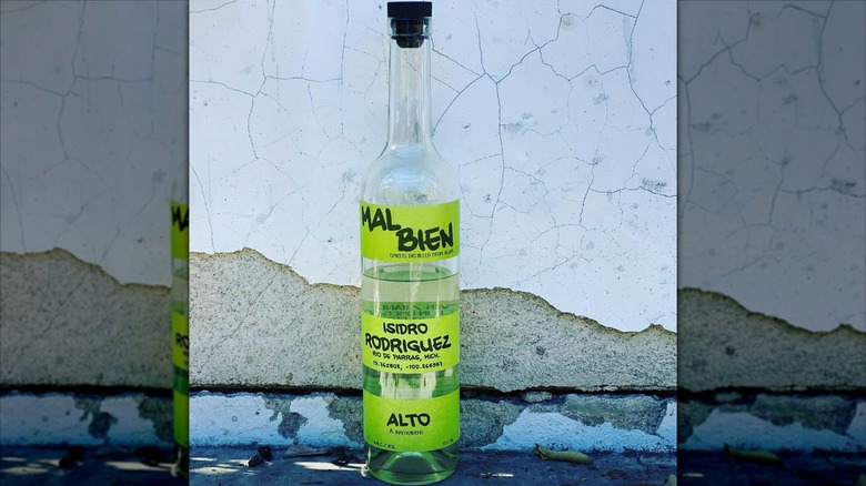 A bottle of Mal Bien Alto mezcal against a cracked wall