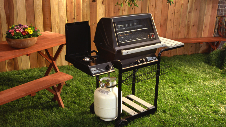 gas grill in backyard setup next to a picnic table
