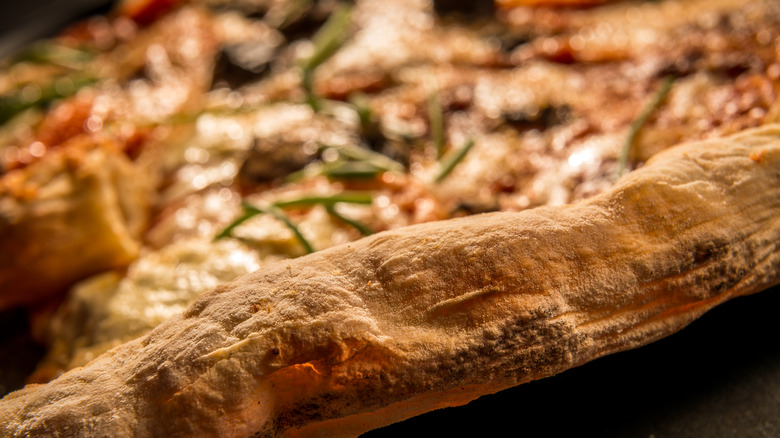 A closeup shows a crispy pizza crust edge