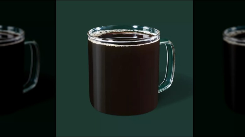 Brewed coffee in a glass mug on a gree background